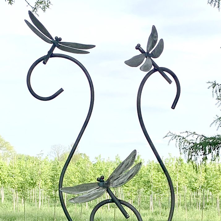Detail shot of metal dragonfly sculptures welded on curly garden stakes.