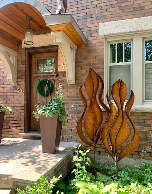 Two large leaf sculptures made of rusted sheet metal and bent metal borders.