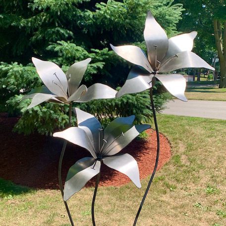 A tall stand of metal lilies rises high above the yard. Left untreated, these flowers will rust.